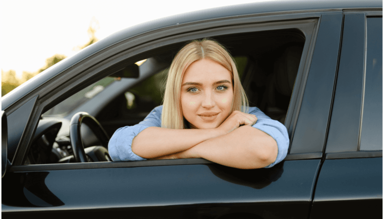 junge Frau schaut aus dem Seitenfenster ihres Autos.